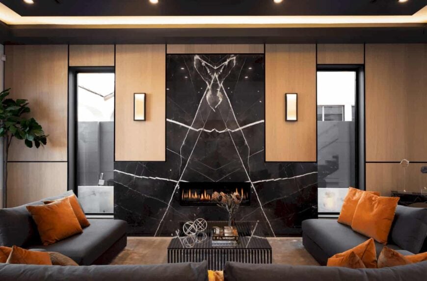 温暖的客厅拥有黑色大理石强调墙，配有现代化的壁炉。它有优雅的木质墙板，由壁灯和凹形天花板灯照明。