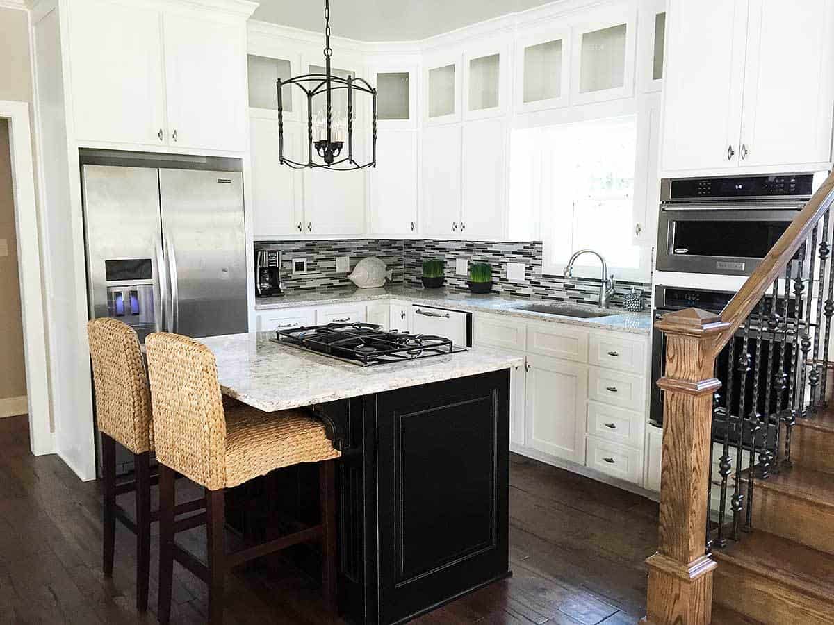 仔细看看厨房里显示了其小厨房岛和早餐酒吧的柳条编织凳子与黑色两岛形成对照的白色大理石台面。