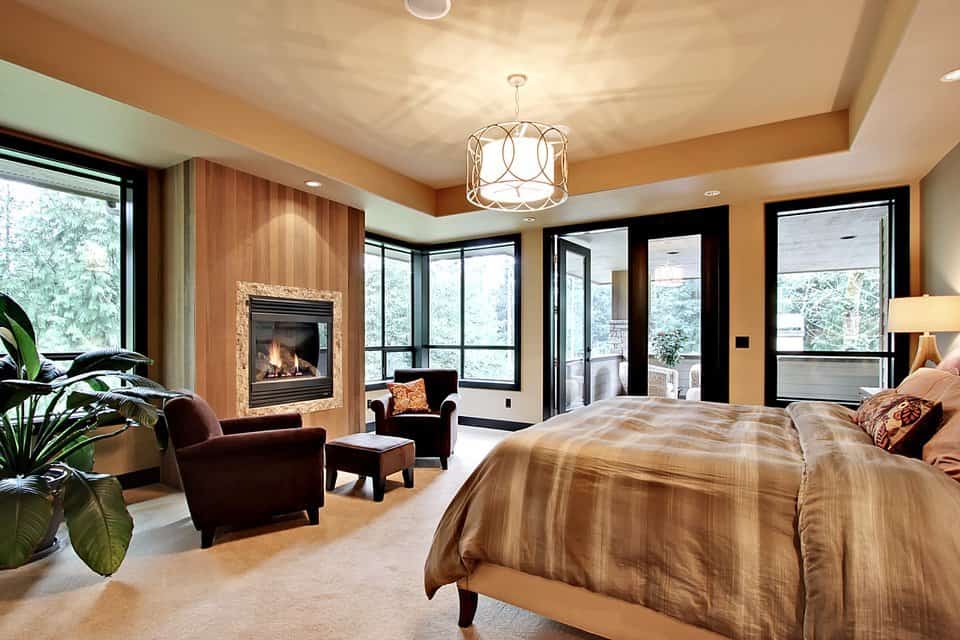 浪漫的壁炉和装饰华丽的鼓吊坠悬挂在托盘天花板上，增强了这间主卧室的温暖氛围。
