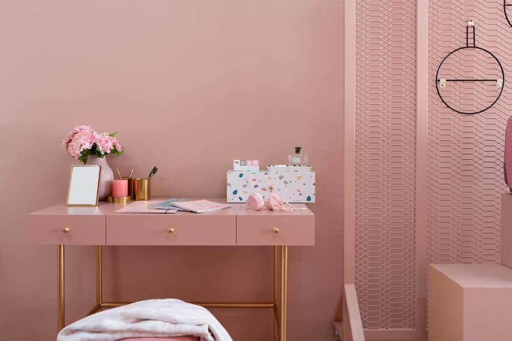 房子里工作区域的特写，粉红色的墙壁与金色的桌子相匹配。