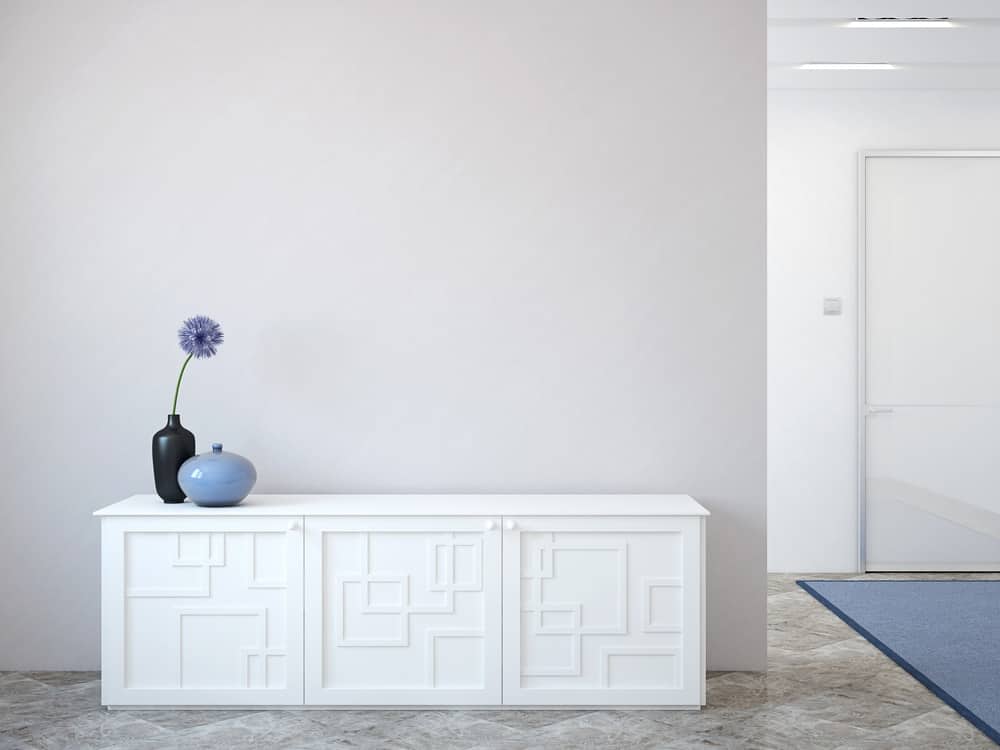 一个简单的门厅，浅灰色的墙壁与白色齐腰高的橱柜相得益彰。
