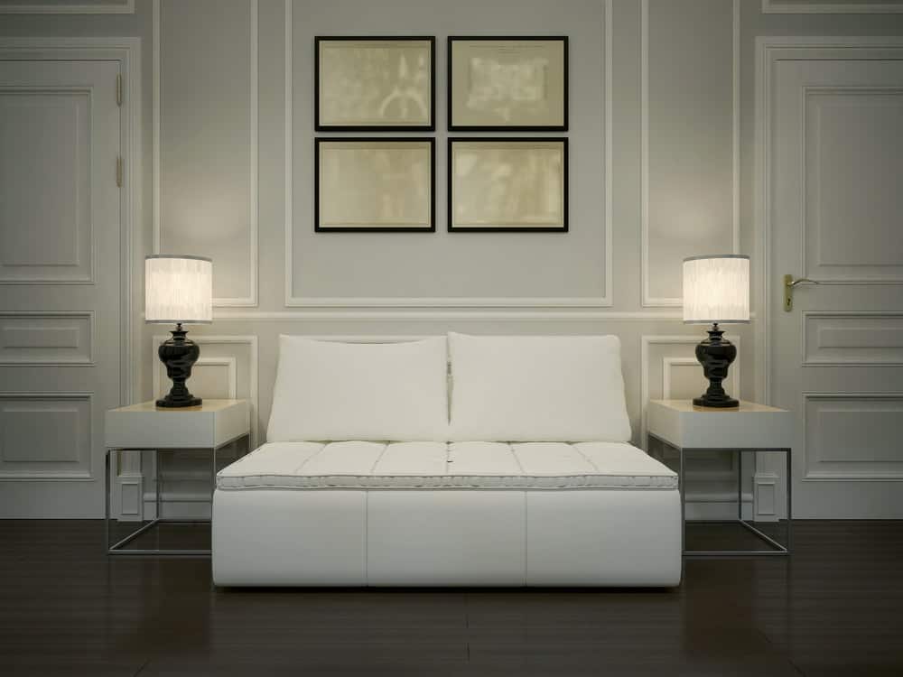 一个豪华的门厅，两盏灯之间有一个白色软垫沙发。