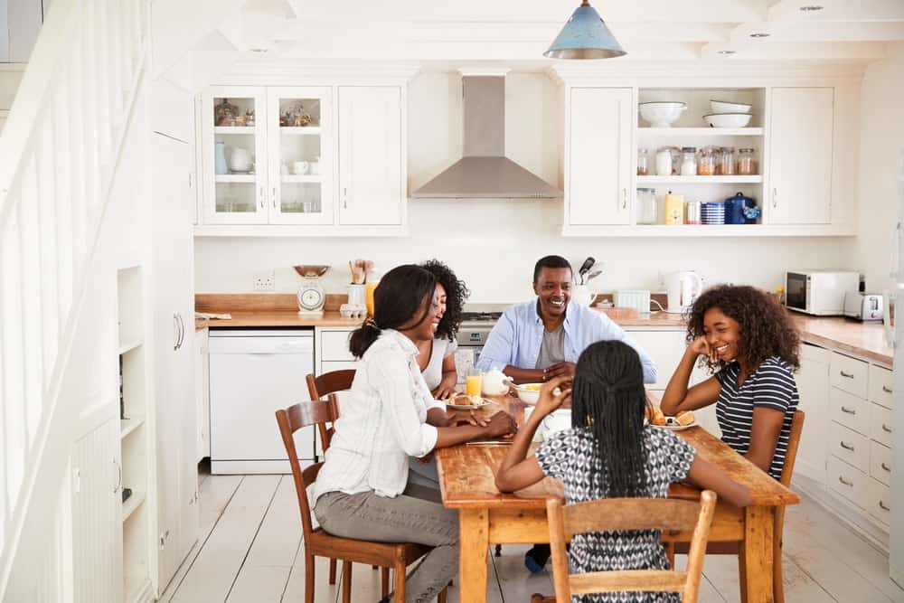 一家人围坐在厨房的木餐桌旁享受早餐。