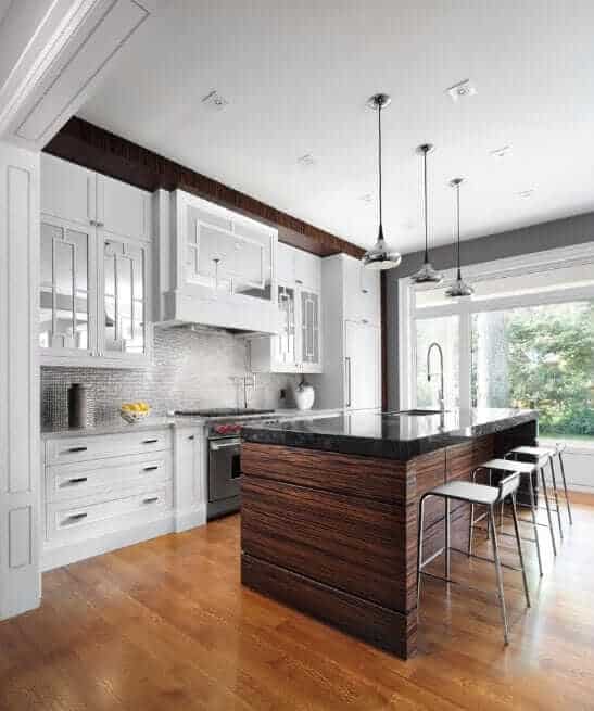 白色厨房设有一个匹配的岛与对比鲜明的黑色台面，完整的用餐座位，和一个内置水槽。