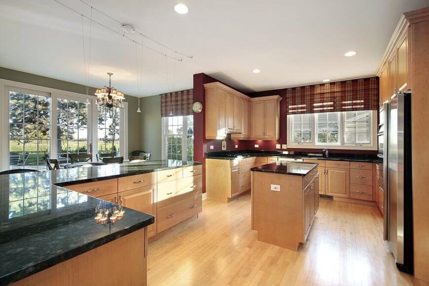 这间厨房采用了浅色的木地板和橱柜，平衡了大胆的墙壁颜色和深色台面