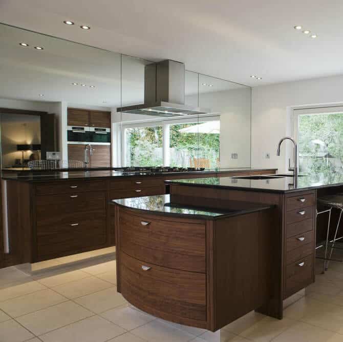 这个有两层岛台的厨房与温暖的天然木材和深色大理石台面的厨房形成对比。