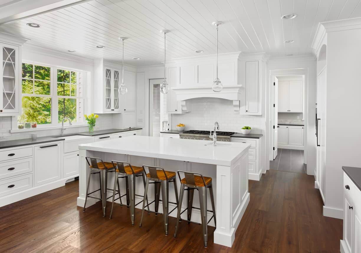 这个厨房的设计非常棒，白色的天花板上有白色的底座吊坠，白色的油烟机，后挡板，岛台。