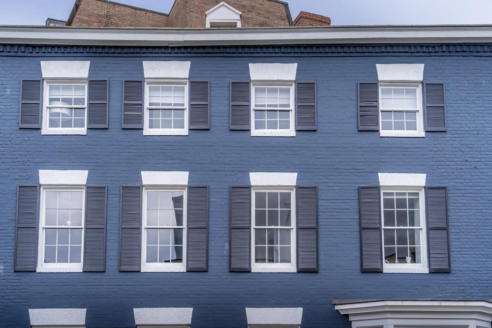 一个豪华的殖民格鲁吉亚风格的联排别墅的外观，对称双盘卷帘窗和蓝色粉刷的砖外观。
