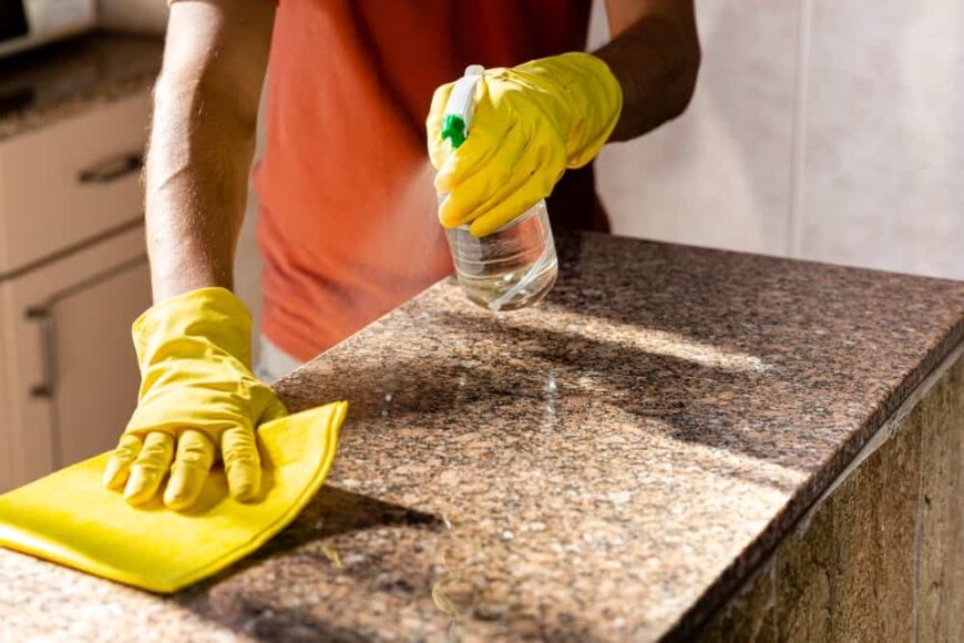 一个男人正在清洗厨房的花岗岩台面。