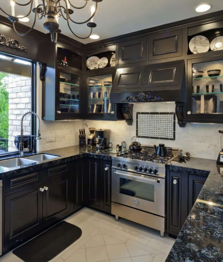 u形厨房，黑色的玻璃橱柜里摆满了装饰性餐具。它包括一个黑色的台面，配备不锈钢延伸和双水槽拉下喷雾器。