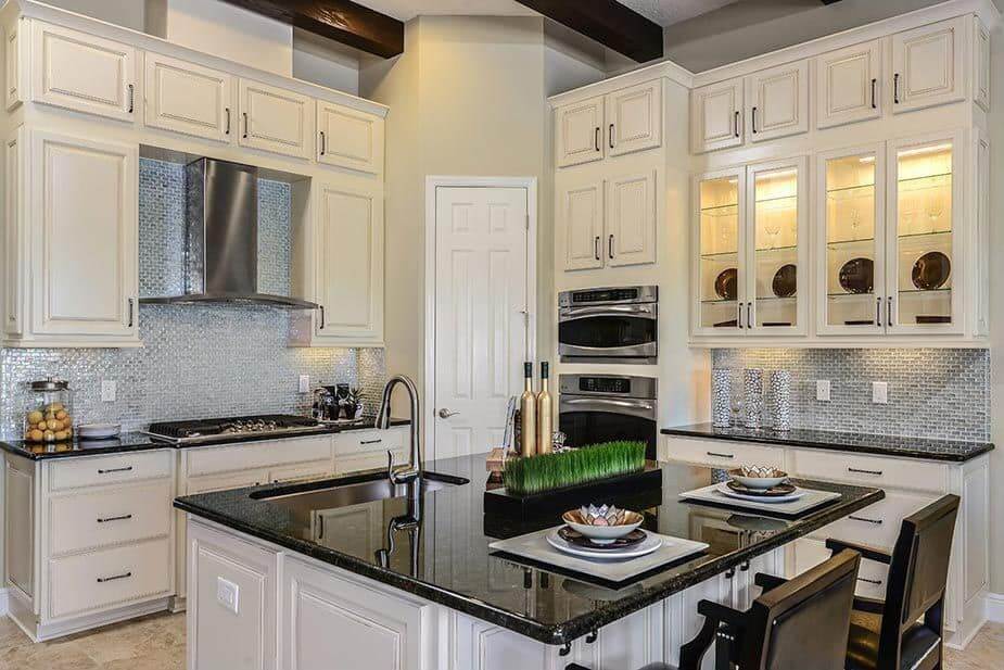这个厨房提供时尚的瓷砖后挡板和优雅的黑色花岗岩台面在厨房柜台和中心岛。