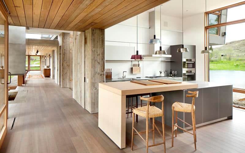 这个优雅的厨房有木制天花板和硬木地板。它还有一张嵌壁式木桌和几把木凳。