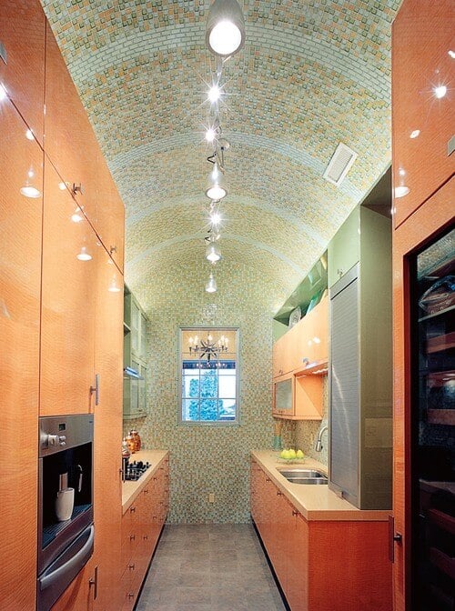 手工制作的玻璃瓷砖在高高的拱形屋顶使这个厨房特别和富有想象力。这个橙色的厨房布置在房间的尽头，在屋顶的光线下看起来是开放的。