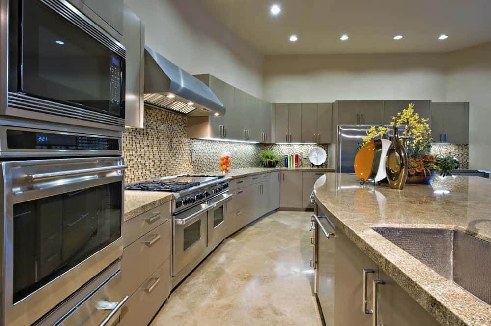 优雅的厨房突出不锈钢电器和深色橱柜，强调了令人惊叹的马赛克后挡板瓷砖。
