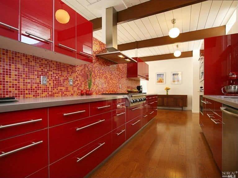 现代的红色厨房硬木地板和红色与橙色瓷砖墙壁以及一些吊灯。