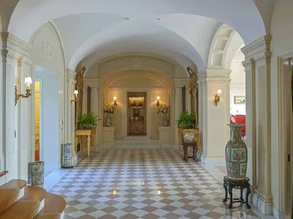 门厅的大理石地板采用米色和白色的格子设计，与腹股沟拱形天花板和两侧的拱形入口非常吻合。