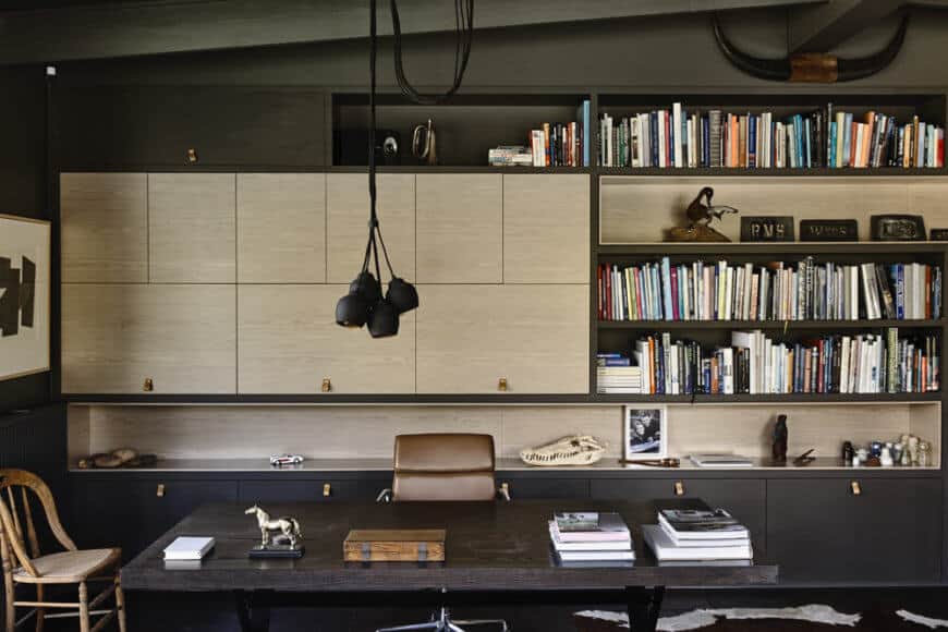 家庭办公室是设计的重要组成部分，这个空间充满了光滑的橱柜和书架，中心是一张黑色的大木桌。浅色木材的外观与主流风格略有不同。