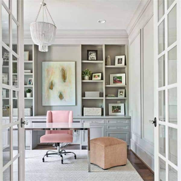家庭办公室有白色的天花板，上面有一盏漂亮的枝形吊灯，镀铬的桌子配上粉红色的办公椅。