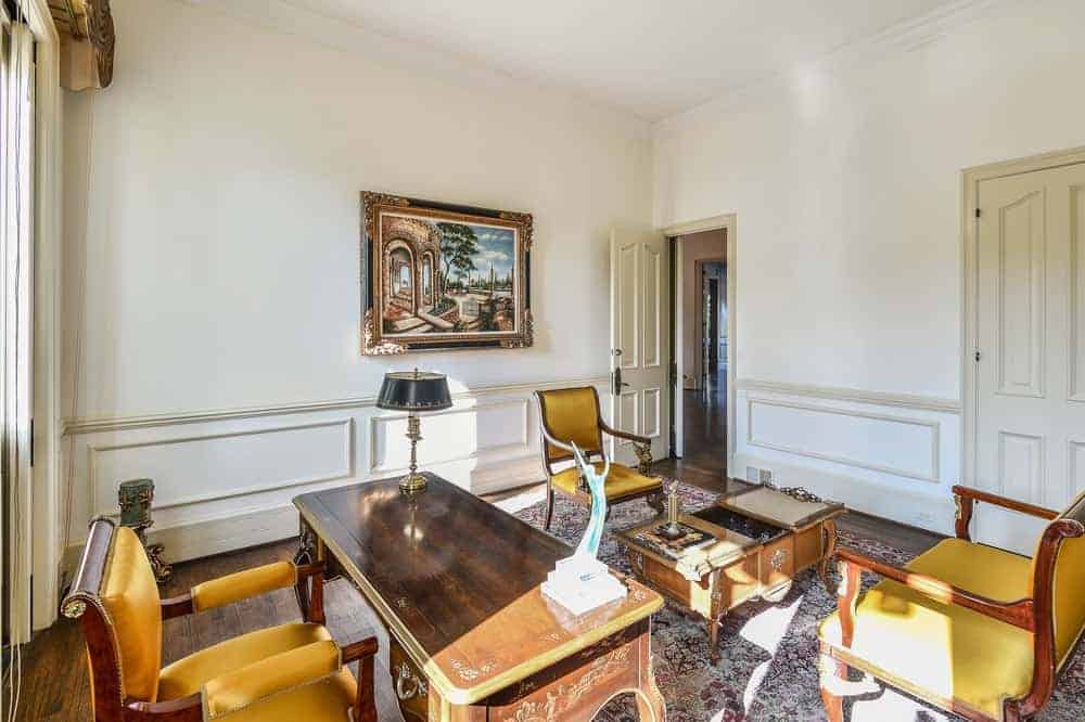 迷人的家庭办公室有一个经典的氛围，它的覆盖，木制的老式工作区域和迷人的扶手椅在设计的地毯地板上。