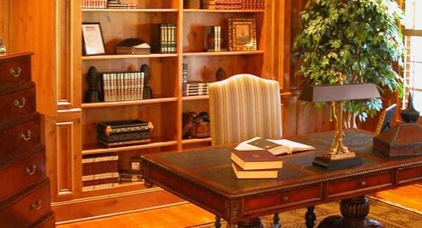 这个家庭办公室的特色是一张经典的木桌，搭配地毯上的条纹高脚椅和嵌入式书架。