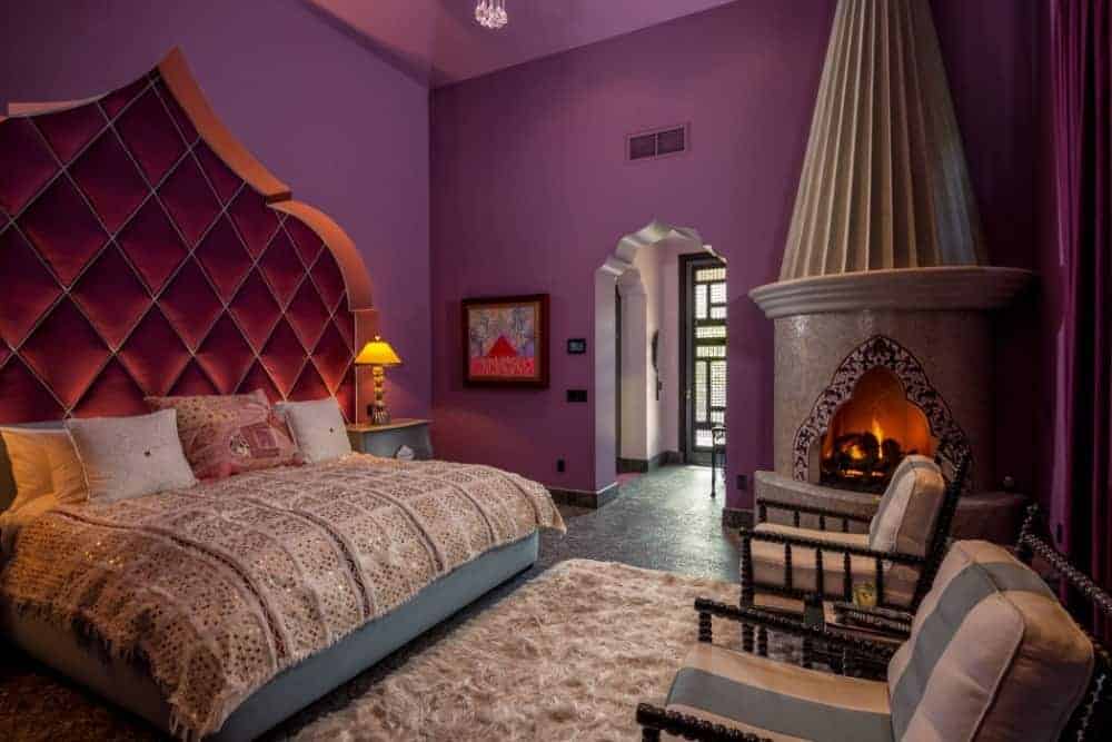 这间主卧以紫罗兰色的墙壁和一张铺在地毯上的特大号床为特色。这间卧室还有独立的壁炉和几把椅子。