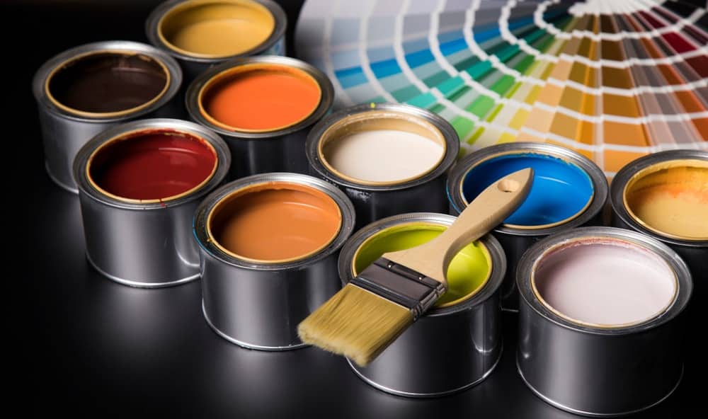 用油漆刷和颜色样品涂不同颜色的罐子。