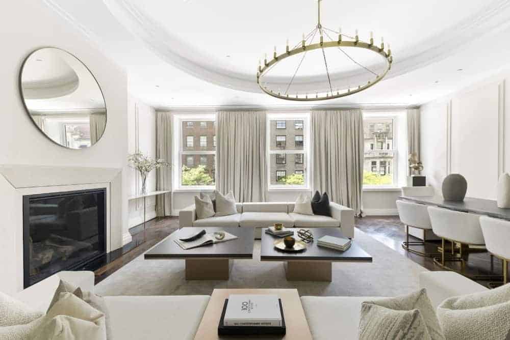 “白色客厅配有一张舒适的沙发和两张咖啡桌，上面铺着时尚的地毯，还有一座壁炉，为起居空间提供温暖。