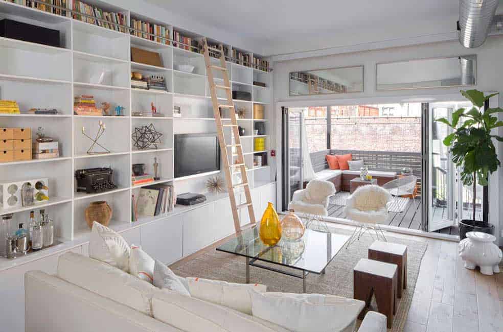 这间客厅配有舒适的沙发和地毯上的玻璃桌，内置书架和木制滚动梯子。