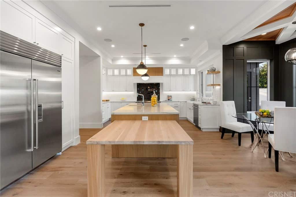 这个迷人而宽敞的厨房展示了大厨房岛的边缘，有一个内置的木桌连接到它。这与硬木地板很相配。