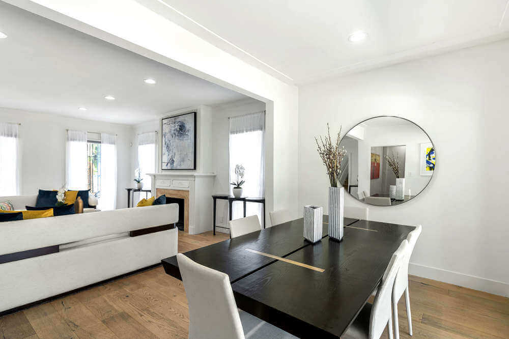 这个简单的和迷人的餐厅有一个黑色长方形的餐桌周围白色现代椅子搭配白色的墙壁和天花板。