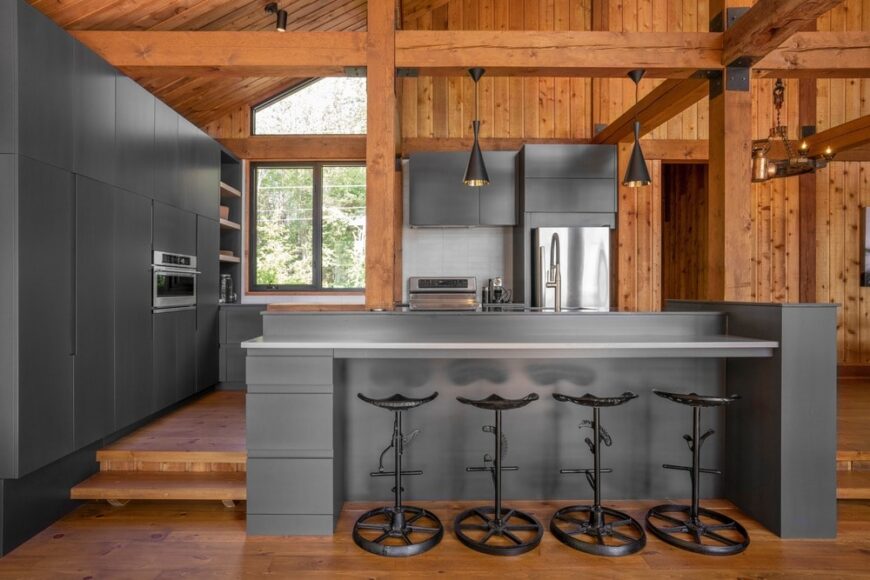这间厨房有现代化的深灰色橱柜，与现代化的电器很相配。这些都是由高天花板的暴露木梁补充的，这些木梁通过厚木柱与厨房岛相连。