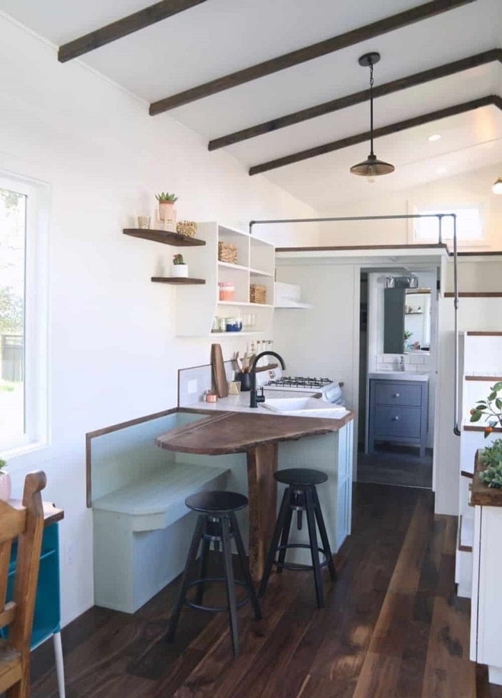 这是一个小厨房，里面有一张嵌壁式的小木桌，配上一张小摊位式的嵌壁式木凳和几把小黑凳子。
