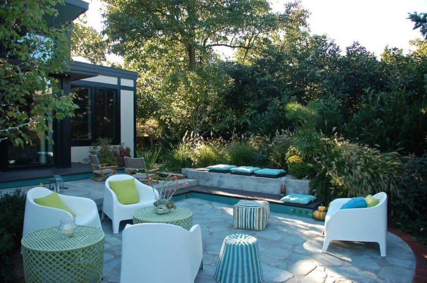 屋后的露台提供了大量新颖的座位选择，白色舒适的椅子和柳条桌子隐藏在屋后丰富的绿色植物中。
