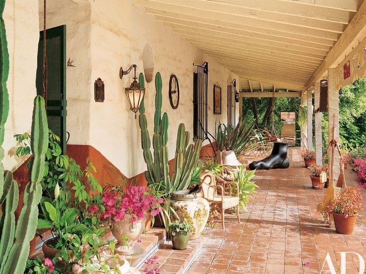 这是房子的露台，里面摆满了装饰性的盆栽植物和雕塑，为这个地区带来了魅力。这具有赤土地板瓷砖，其转向它旁边的花园。