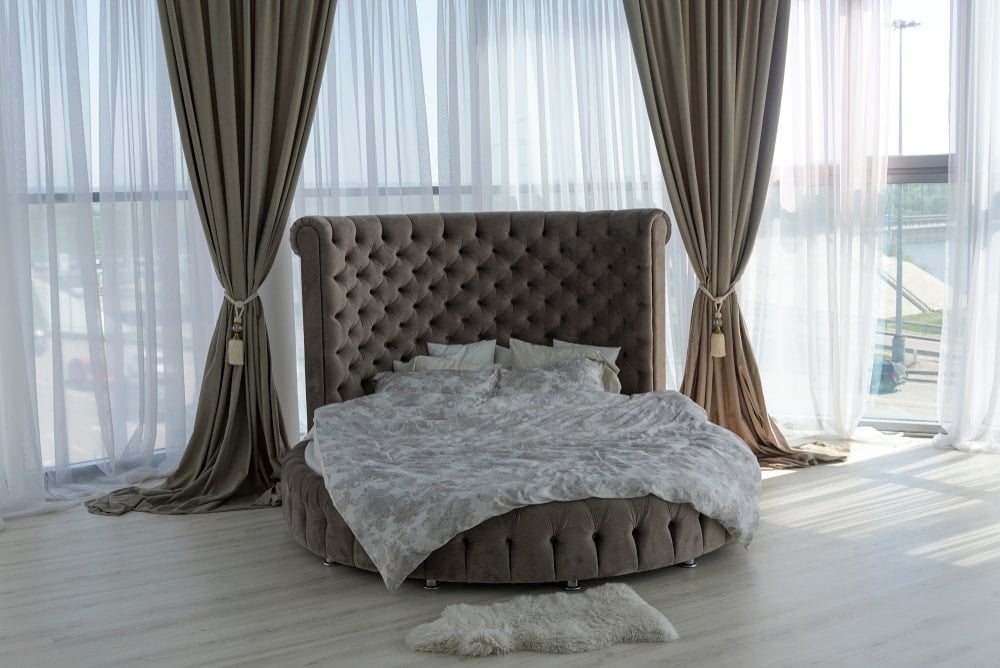 豪华卧室，配有圆形床和全长窗帘和窗户。