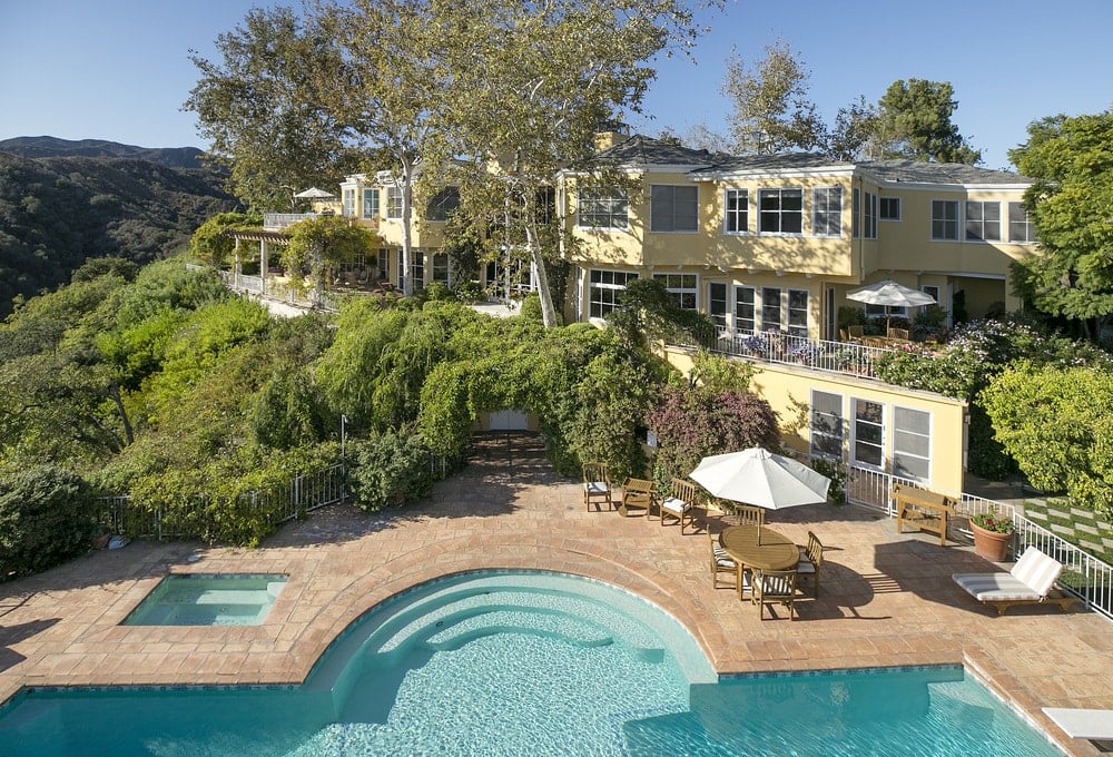 这张房子后面的鸟瞰图以美丽的游泳池和郁郁葱葱的绿色景观为特色，与房子美丽的米黄色外墙相得益彰。图片来自Toptenrealestatedeals.com。