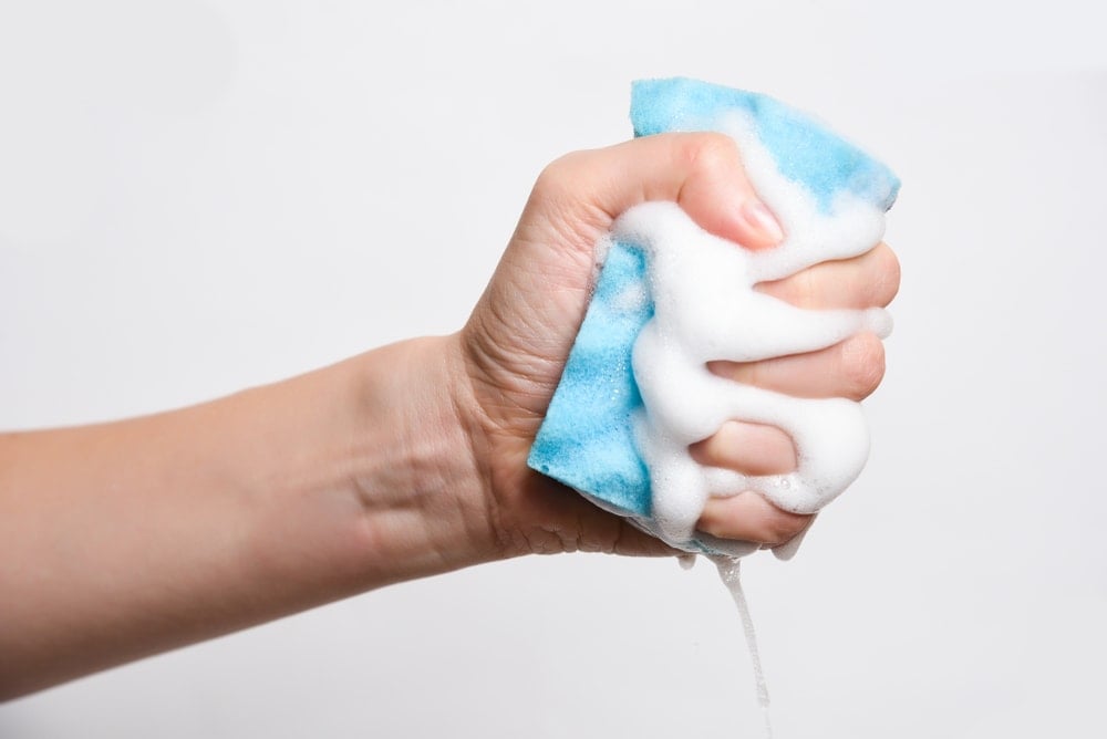 一只手在挤压肥皂海绵。
