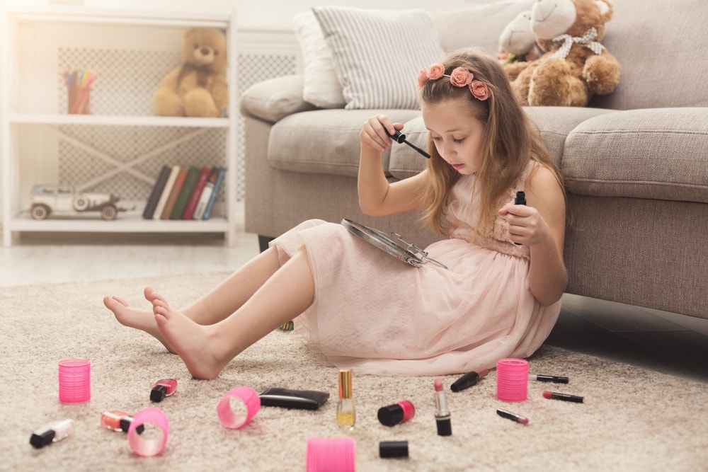 一个女孩在客厅的地毯上玩她妈妈的化妆品。