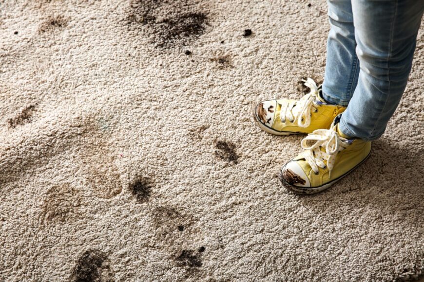 近距离观察一个穿着泥泞的鞋子走在泥泞地毯上的人。