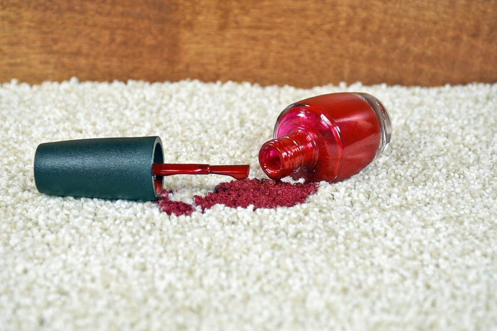 仔细看洒在地毯上的一瓶红色指甲油。