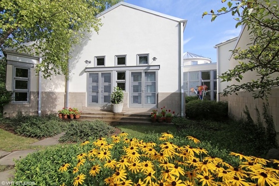 这是一个从后院花园的房子。这里你看到五颜六色的开花灌木和绿化,给颜色浅肤色房子的外墙。图片由Toptenrealestatedeals.com。