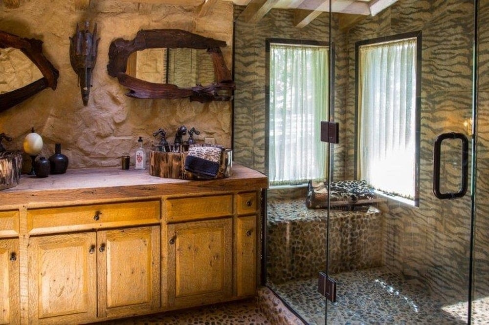 这是一个木制梳妆台，上面有一个独立的水槽和一面镜子。旁边是玻璃围成的淋浴区。图片来自Toptenrealestatedeals.com。