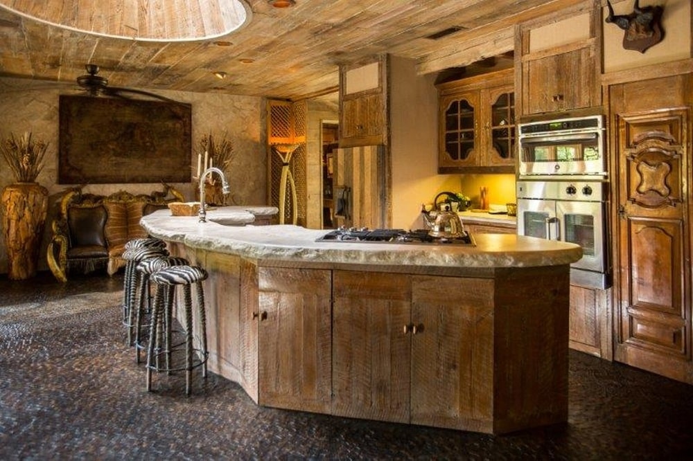 这个厨房有一个大的弧形厨房岛台，它的木质色调与烹饪区的木质橱柜相匹配。图片来自Toptenrealestatedeals.com。