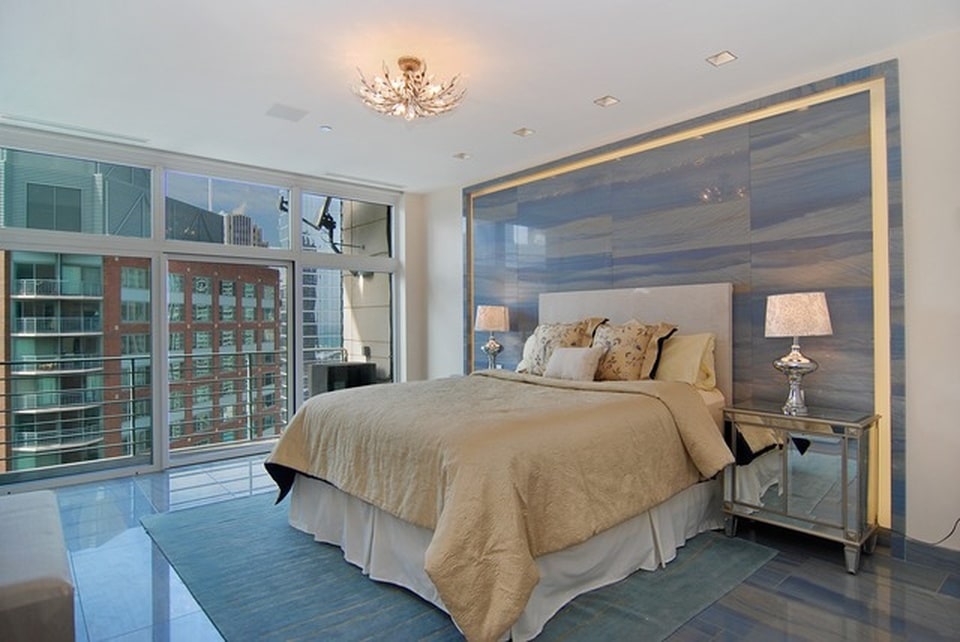 这间卧室的米色软垫床头板与后面和两侧的台灯形成对比。图片来自Toptenrealestatedeals.com。