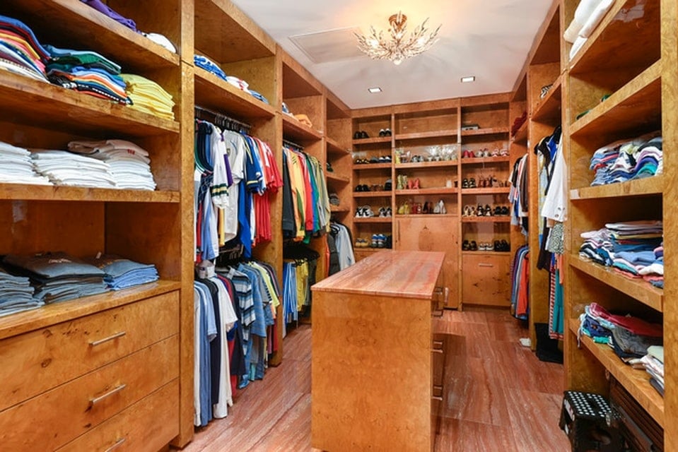 这是更衣室和步入式衣橱，里面有木制橱柜，有架子和衣架。图片来自Toptenrealestatedeals.com。
