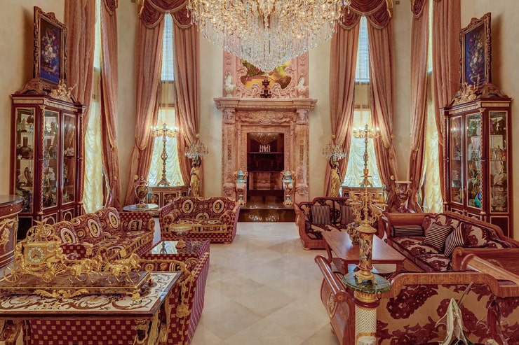 这是这栋房子的正式客厅，里面有几套带有金色装饰的家具，中间有一条走廊，通往另一端的大壁炉。图片来自Toptenrealestatedeals.com。