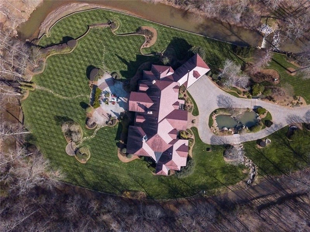 这是大房子的俯视图，展示了陶土色调的屋顶，各种天窗在周围的绿色景观中脱颖而出。图片来自Toptenrealestatedeals.com。