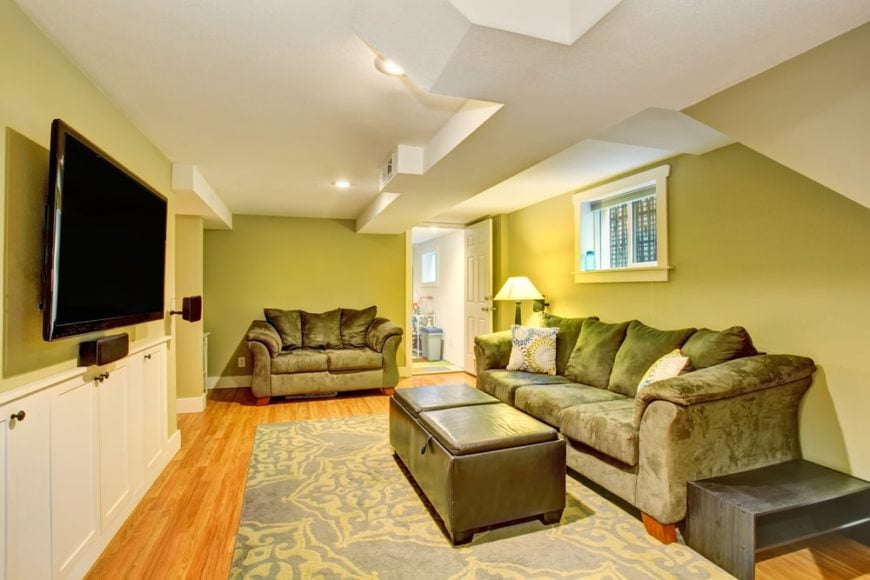 这间家庭娱乐室的墙壁是绿色的，沙发是灰色的，天花板是白色的，与护壁板相配。
