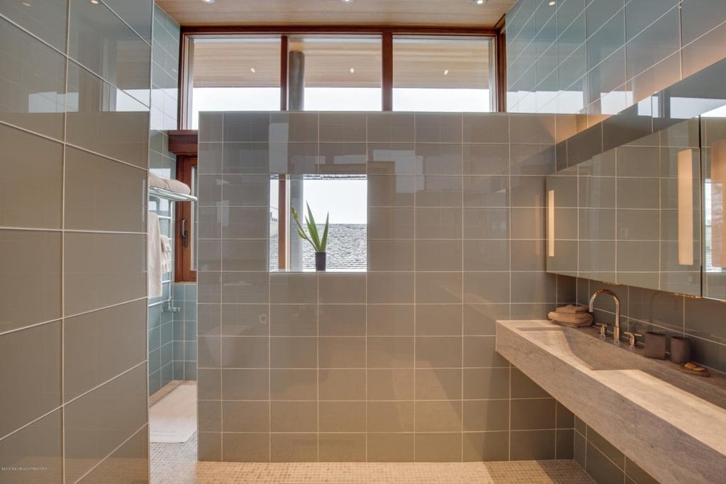 另一间浴室有一个浮动水槽，与通往淋浴区的隔板上的瓷砖相匹配。图片来自Toptenrealestatedeals.com。