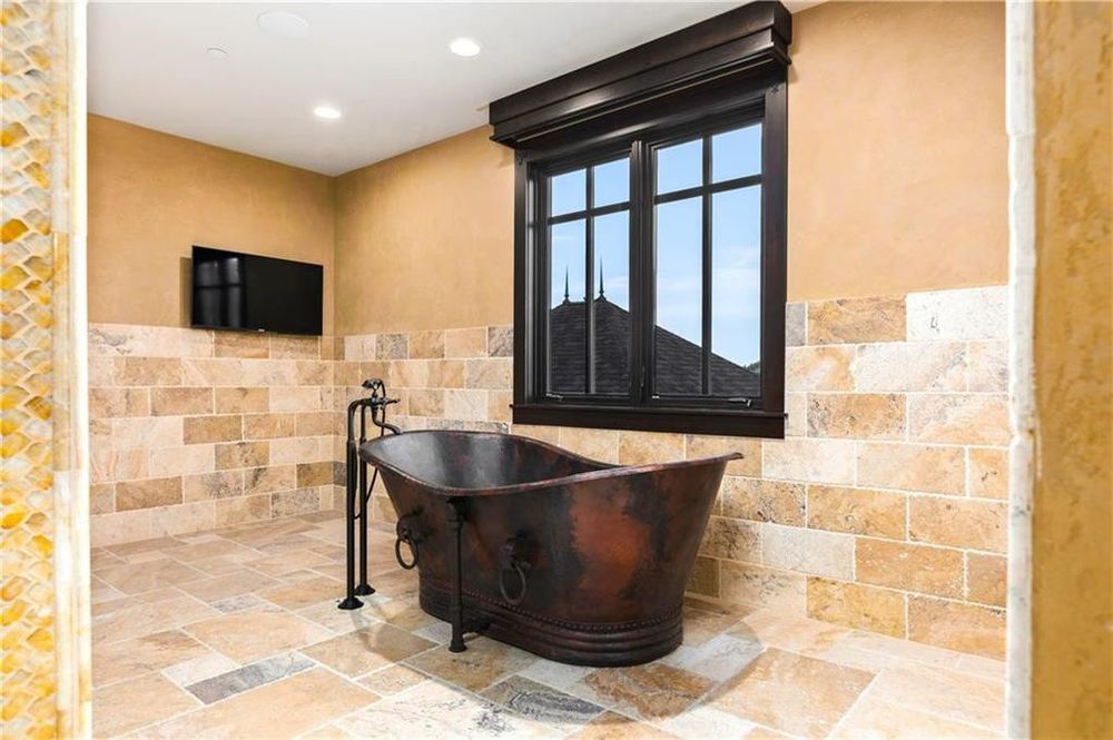 这是浴室的独立式浴缸的暗色调匹配窗口框架。这些坚决反对米色色调的地板,墙壁和天花板。图片由Toptenrealestatedeals.com。